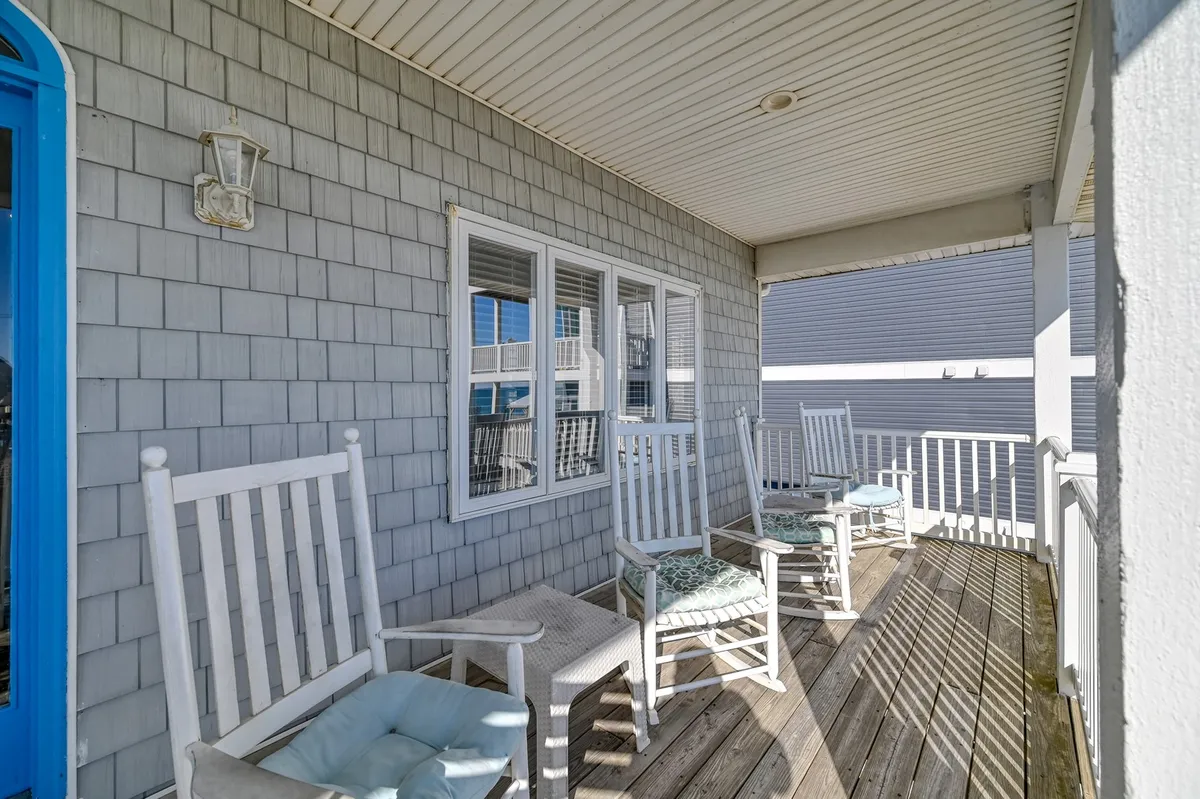 An exterior shot highlights a cozy porch with classic rocking chairs, a bright blue door, and shingle siding. This inviting entryway feels quintessentially coastal and hints at leisurely moments spent relaxing after a day of exploring local attractions.