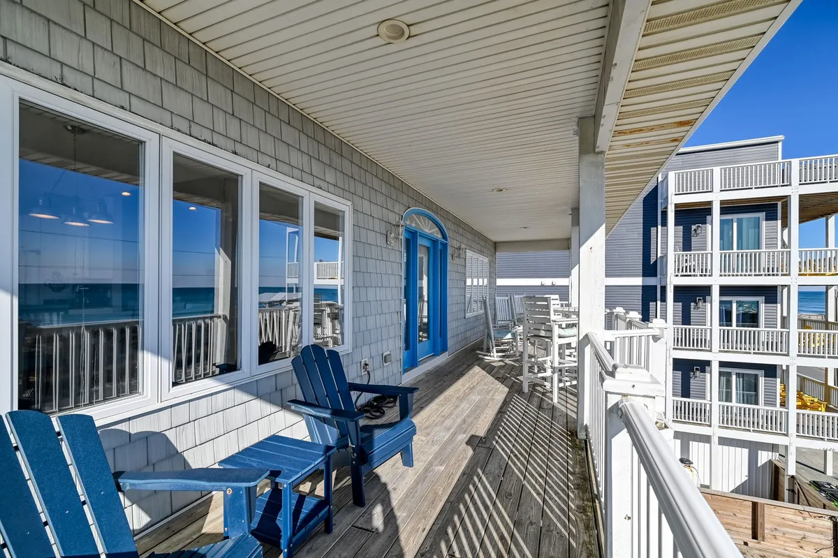A scenic exterior features a blue front door, Adirondack chairs, and an ocean view. The setting suggests a peaceful and social outdoor space, ideal for evening gatherings after family adventures around town.